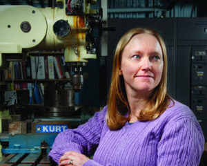 Amber McClung, Ph.D., who teaches Mechanical Engineering, poses with equipment in her lab.