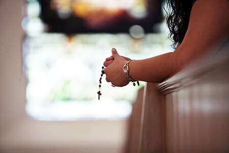 A lady holding prayer beads in a chapel on St. Mary's campus