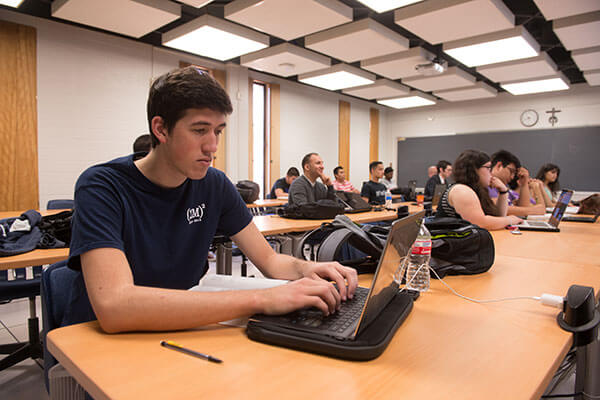 Computer Science student works on laptop in class.