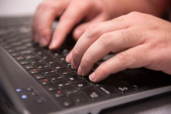 Hands of student typing on laptop.