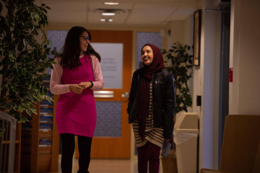 Two students walk through a hallway smiling