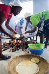 Haitian women making bread over a wood fire