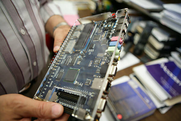 Djaffer Ibaroudene, Ph.D., holds a circuit board.