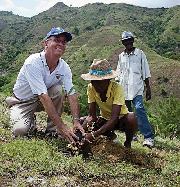 Tom Mengler helps plant a tre in Haiti