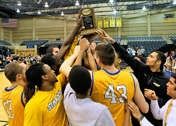 St. Mary's Men's Basketball holding Heartland Conference championship trophy in 2014-2015 season.