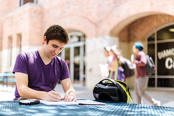 Student does homework in front of the University Center.