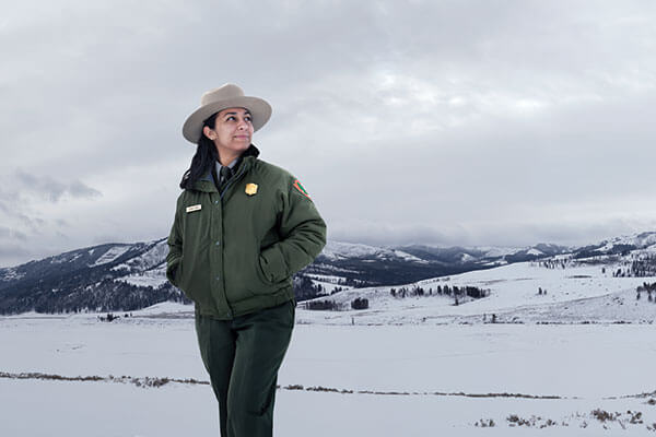 Lianna Duran in her ranger uniform, standing in front of snow-capped mountains