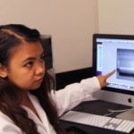 A nursing student points to a computer screen with test results