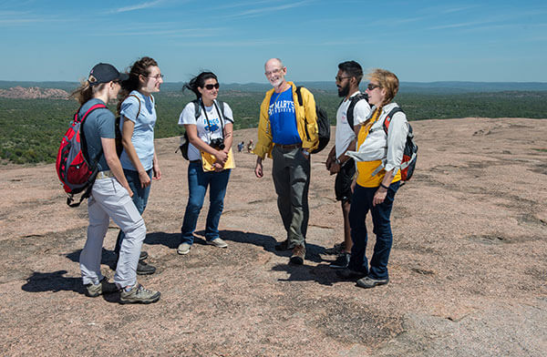 St. Mary's University Environmental Science professors and students standing on the summit of Enchanted Rock.