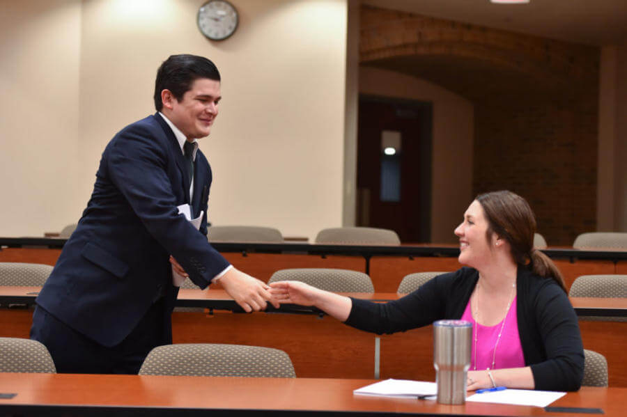Two law students shaking hands in a classroom