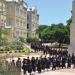 Students in regalia process by the Bell Tower to their commencement.