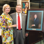 Ronald Herrman and wife Karen stand next to his portrait.
