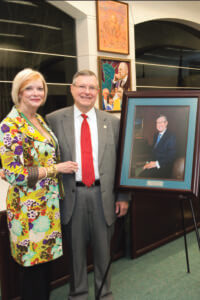 Ronald Herrman and wife Karen stand next to his portrait.