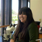 Student stands by microscope.
