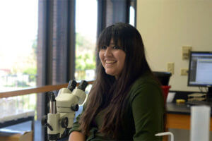 Student stands by microscope.