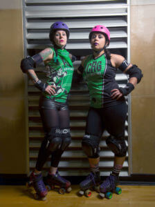 Samantha Franklin and Melanie Call stand in full roller derby gear.