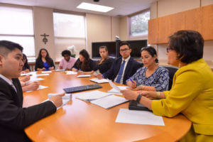 Dean Singh speaks with a diverse group of students around a table.