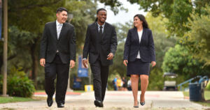 Students in suits walk across campus.