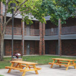 Cremer Hall courtyard, a patio area with two picnic tables surrounded by the brick building