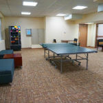 Wide view of a Chaminade lounge featuring a ping-pong table, mailboxes, and a vending machine