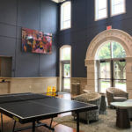 Side view of a Founders Hall common room, featuring a ping-pong table and grand entryway