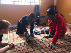 Psychology professor Jillian Pierucci, Ph.D., with a caregiver and child in Zambia