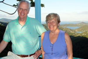 Jim Drought poses on a balcony overlooking a water view with Anita Branch