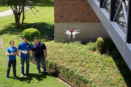 Senior engineering students outside the UC with a drone