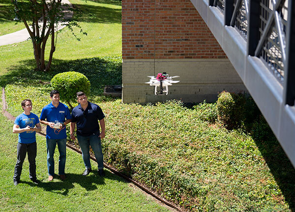 Senior engineering students outside the UC with a drone