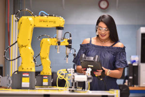 A female engineering student uses a robotic arm to work in a lab.