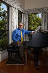 Law alum, Claude Ducloux sitting at piano in his Austin home.