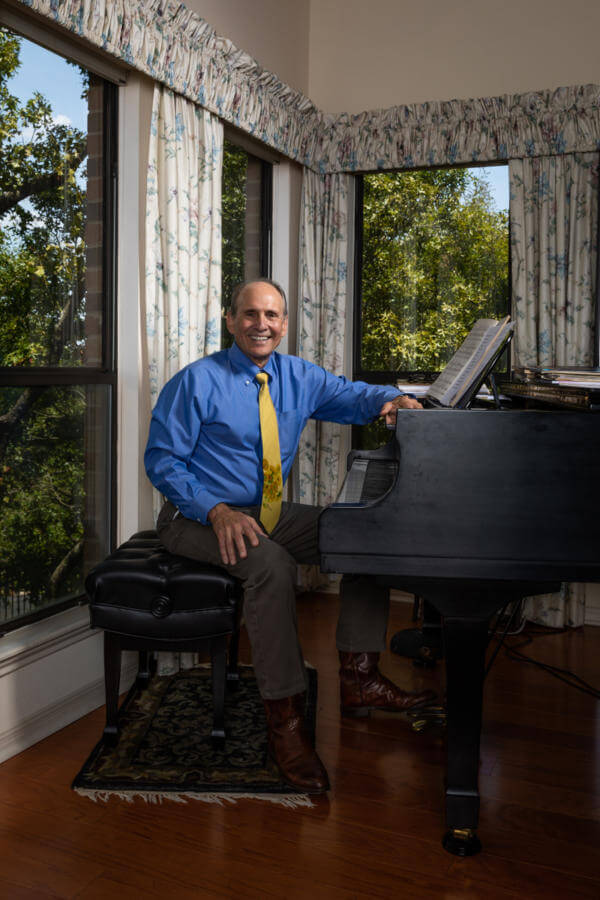 Law alum, Claude Ducloux sitting at piano in his Austin home.