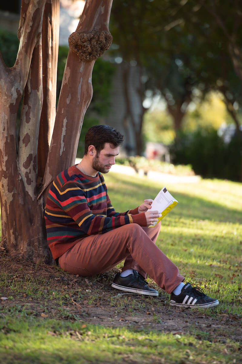 student sitting under a tree and reading