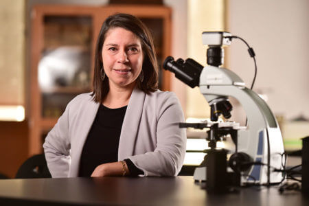 Veronica Contreras-Shannon stands by a microscope.