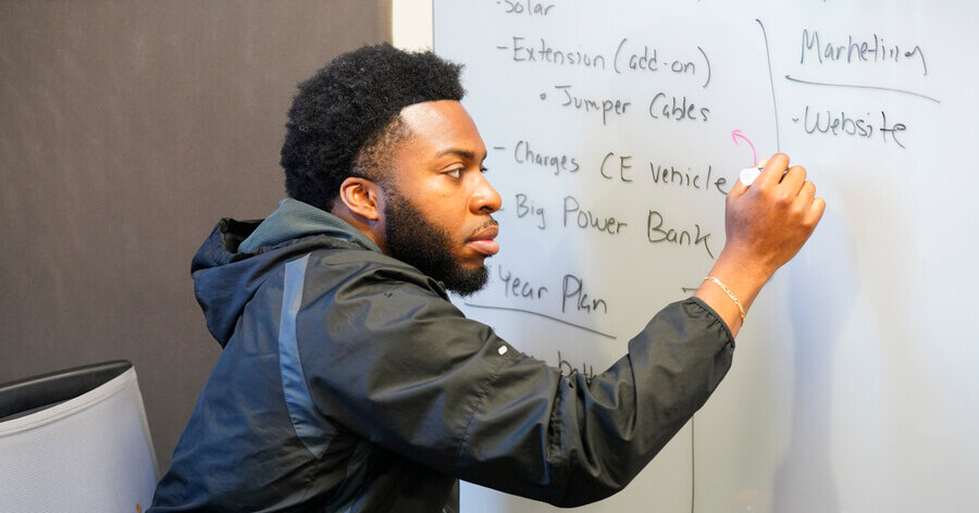 Graduate student writing on a whiteboard in a black jacket at St. Mary's University in Graduate Center for Excellence