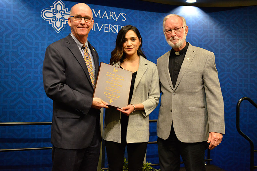 Leslie Alvarez accepts award from President Mengler and Father Eden.