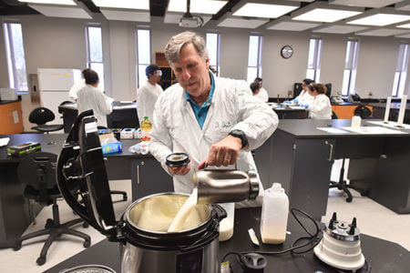 Gary Ogden pours milk in the lab for an experiment
