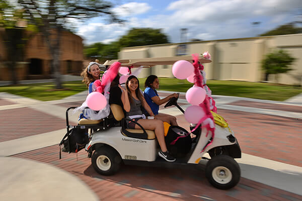 Students participate in the golf cart parade during Homecoming