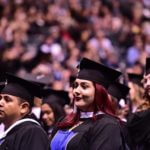 focus on female student in crowd surrounded by classmates at graduation