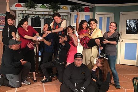 A group of theatre students posing in silly ways with the set behind them