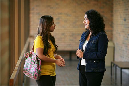 professor speaking to student in outdoor hallway