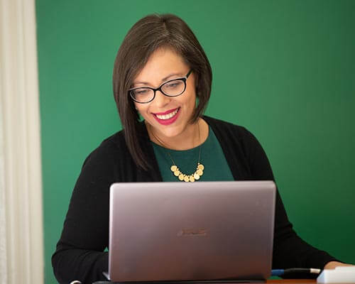 professor smiling while looking at laptop