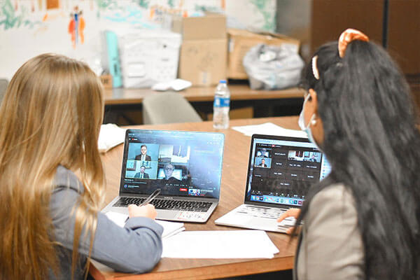 Two law students sit side by side looking at Zoom computer screens.