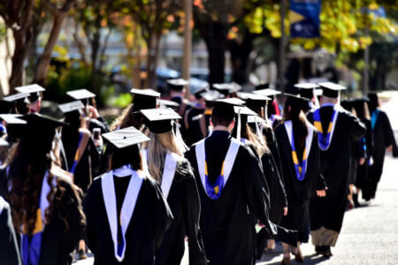 Graduates process into the arena in their caps and gowns