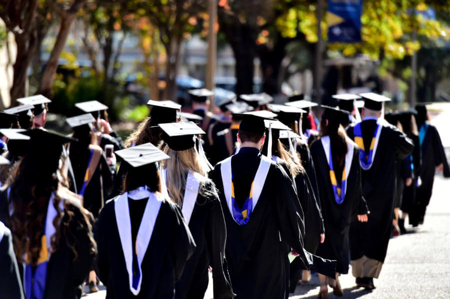 Graduates process into the arena in their caps and gowns.