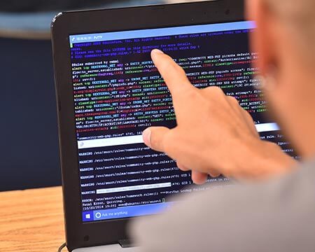 close up of cybersecurity student pointing at screen of code