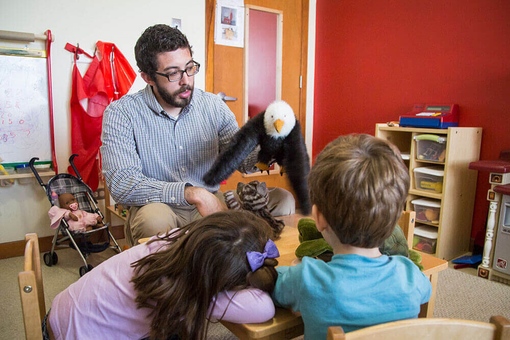 family life center counselor showing stuffed animal eagle to two children