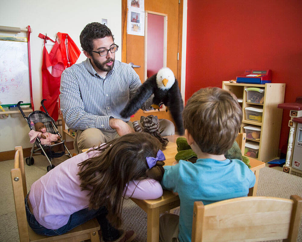 family life center counselor showing stuffed animal eagle to two children