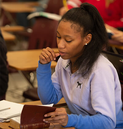 A female student reading a Bible in class.