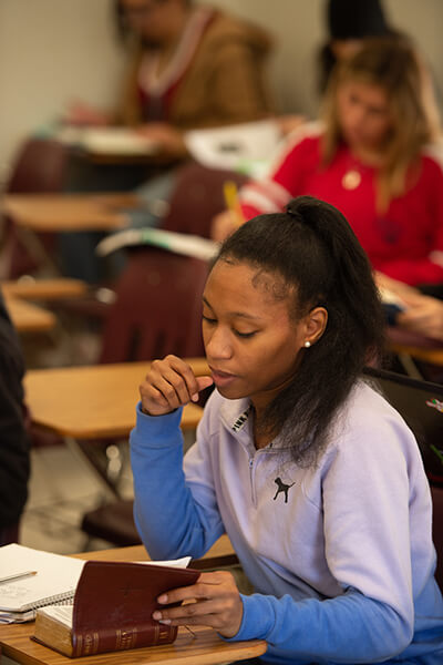 A female student reading a Bible in class.